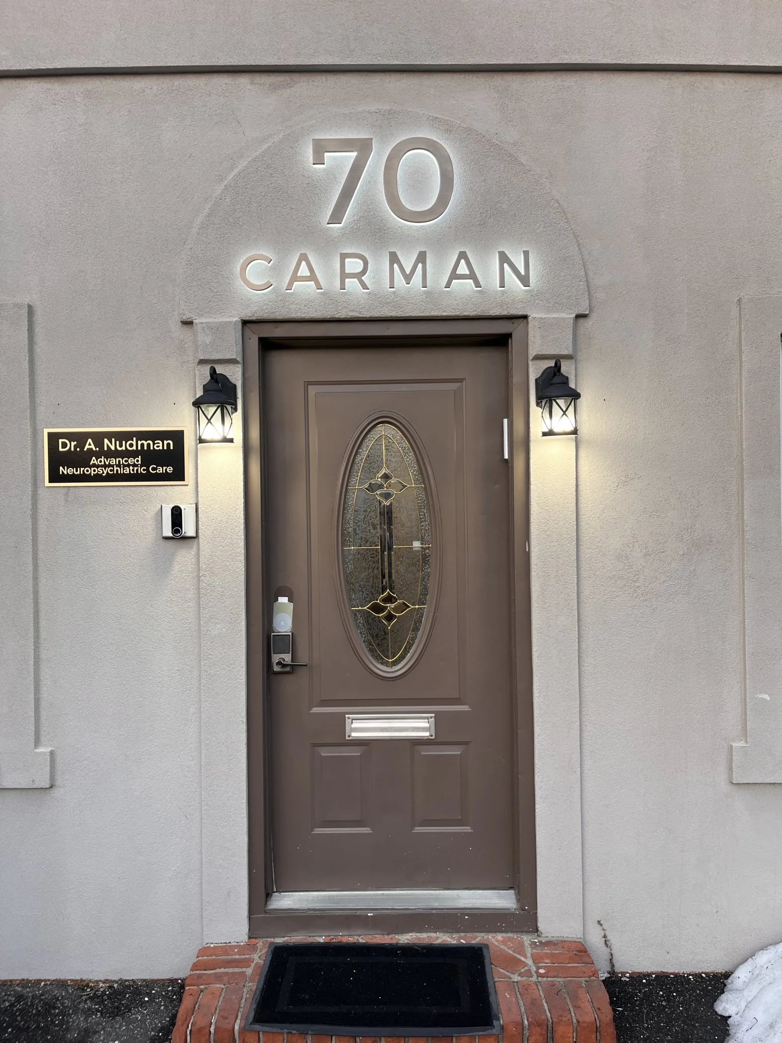 Entrance to Dr. A. Nudman Advanced Neuropsychiatric Care at 70 Carman, with brown door and illuminated address sign